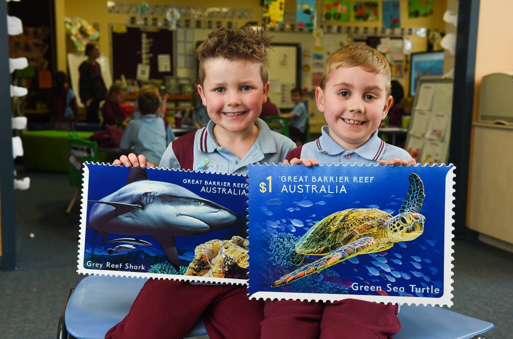 POSTING KNOWLEDGE: Hunter Russell, 6, and Darcy Harvey, 6, with the oversized 'Reef Safari' stamps. Picture: MARK JESSER