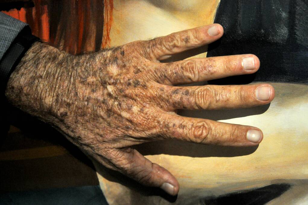 Charles Waterstreet compares his hand to the skin of a model painted in a portrait of him. Picture: PETER DE KRUIJFF