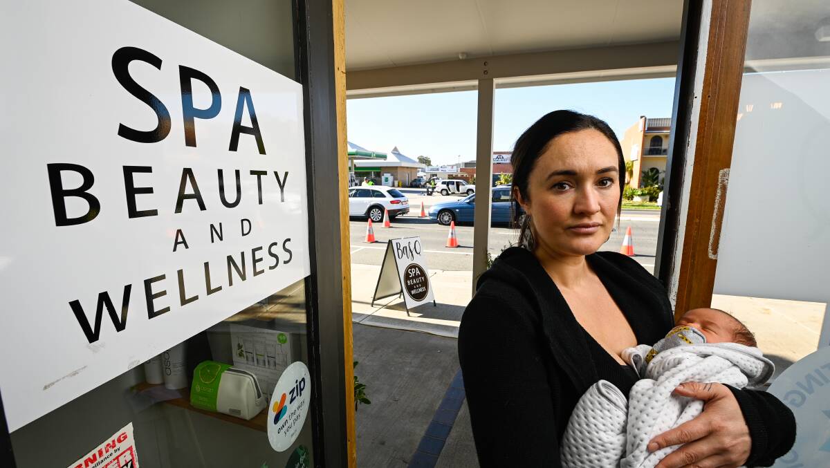 Courtney Callesen with her baby son at her Albury business where a border checkpoint is located in front of her business. Picture: MARK JESSER