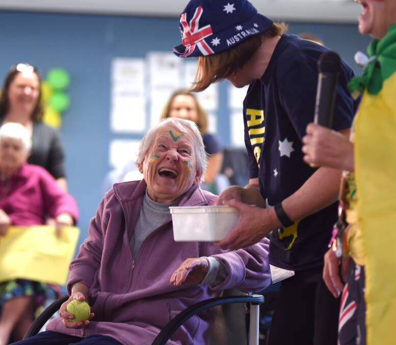 VYING FOR VICTORY: Lutheran Dellacourt resident Mary Emson dons some green and gold facepaint for the activities day. She laughed as her team cheered her on at the box bowls event. Picture: MARK JESSER