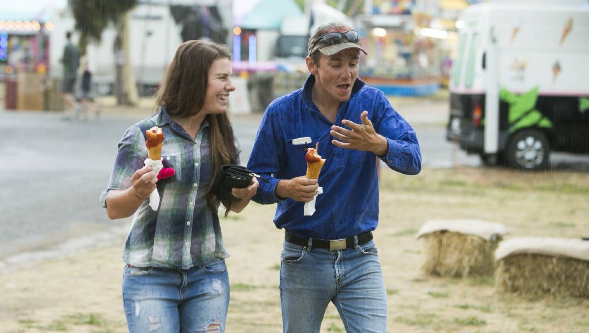 FUN DAY: A pair of showgoers enjoy some hot food in the rain at the Albury Show. Picture: ELENOR TEDENBORG