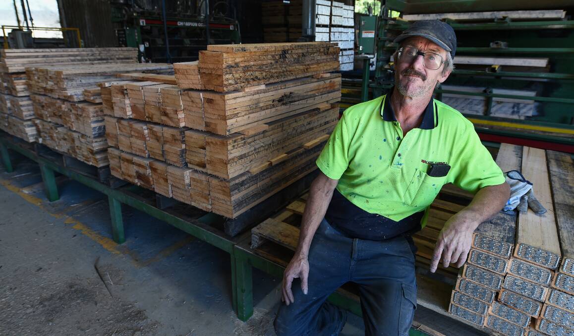 Grim outlook: Walkers Sawmill worker Stephen Williams with planks that are formed into pallets for the CHEP company. He feeds the timber into a machine which then nails the struts to form the pallets. Picture: MARK JESSER