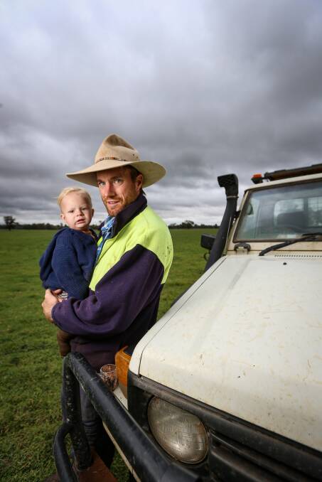 RAIN WELCOME: Farmer Jordan Schilg with his youngest child Colby, 1, on his Brocklesby farm where they received close to 80mm of rain. Pictures: JAMES WILTSHIRE