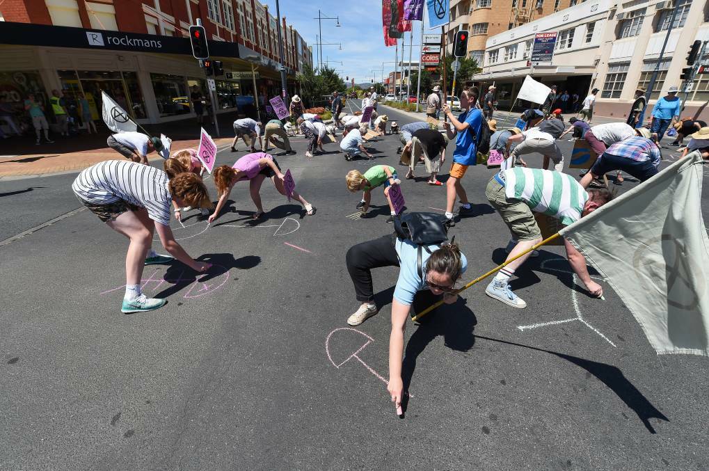 FIRST ACTION: Extinction Rebellion protesters draw dead fish in chalk on Albury's main intersection during action in December.