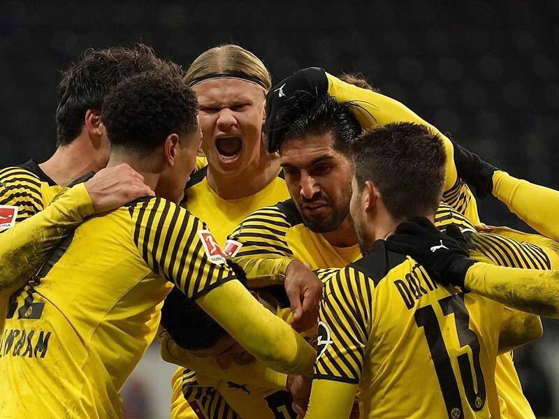 Borussia Dortmund teammates mob Mahmoud Dahoud (centre) after his late winner against Frankfurt.