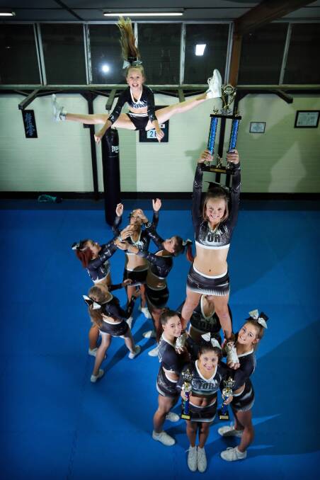 Danielle Hartley (in the air, left), 12, and her sister Britney Hartley (holding trophy), 10, and their fellow Hume Dance School cheerleaders have won sections at the Australian All Star Cheerleading Federation’s Queensland Winterfest competition. Picture: MATTHEW SMITHWICK