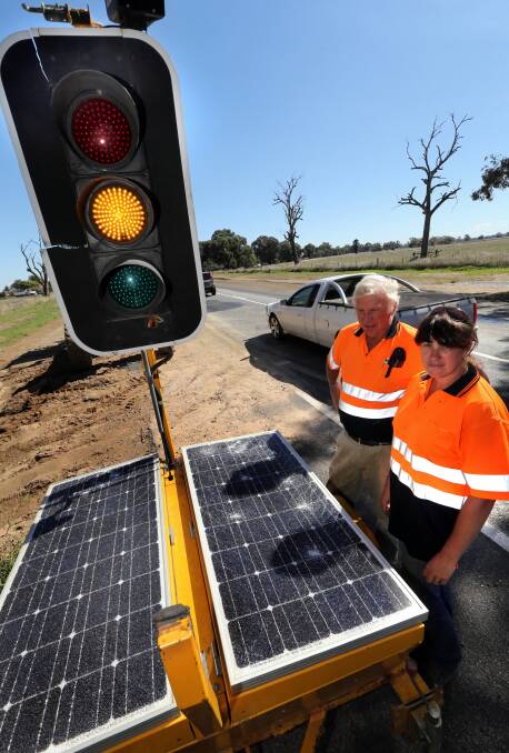 Road contractor Geoff Crameri and his daughter Janine Pregnall with the mobile traffic light which had its solar panels smashed. Picture: PETER MERKESTEYN