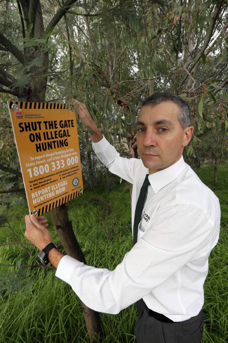 Troy Hogarth fixes a sign aimed at illegal hunters. Picture: PETER MERKESTEYN