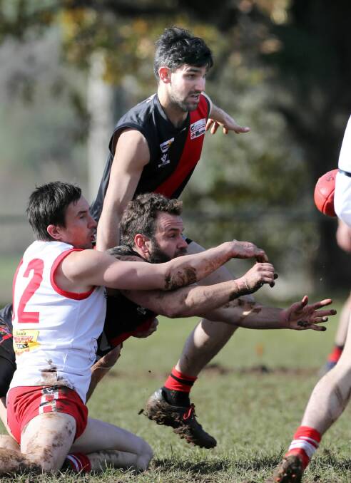 Chiltern star Mark Doolan knocks the ball clear of Dederang-Mt Beauty’s Dale Lappin and Jason Gentile as the Swans came from 36 points down at quarter-time to roll the Bombers. Pictures: PETER MERKESTEYN