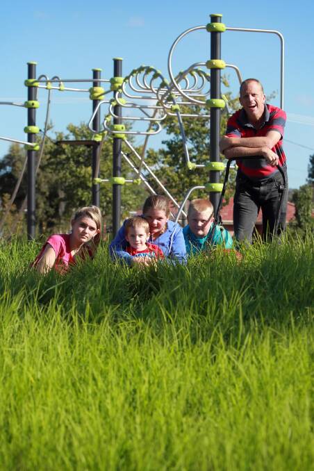 Emma, 13, Nathan, 3, Teagan, 12, Riley, 8, and Shane Carmosin sit in Dr John Schlink Park, near McGeoch Court, Wodonga, which has not been mowed in a month. Picture: MATTHEW SMITHWICK