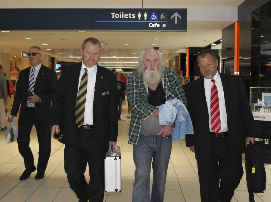 Colin Michael Newey is escorted by police at Sydney Airport after being arrested for murder in July.
