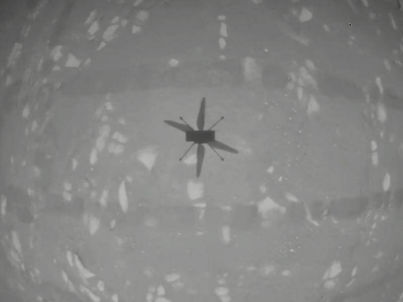 An image from Mars shows the Ingenuity helicopter casting a shadow as it hovers above the surface.