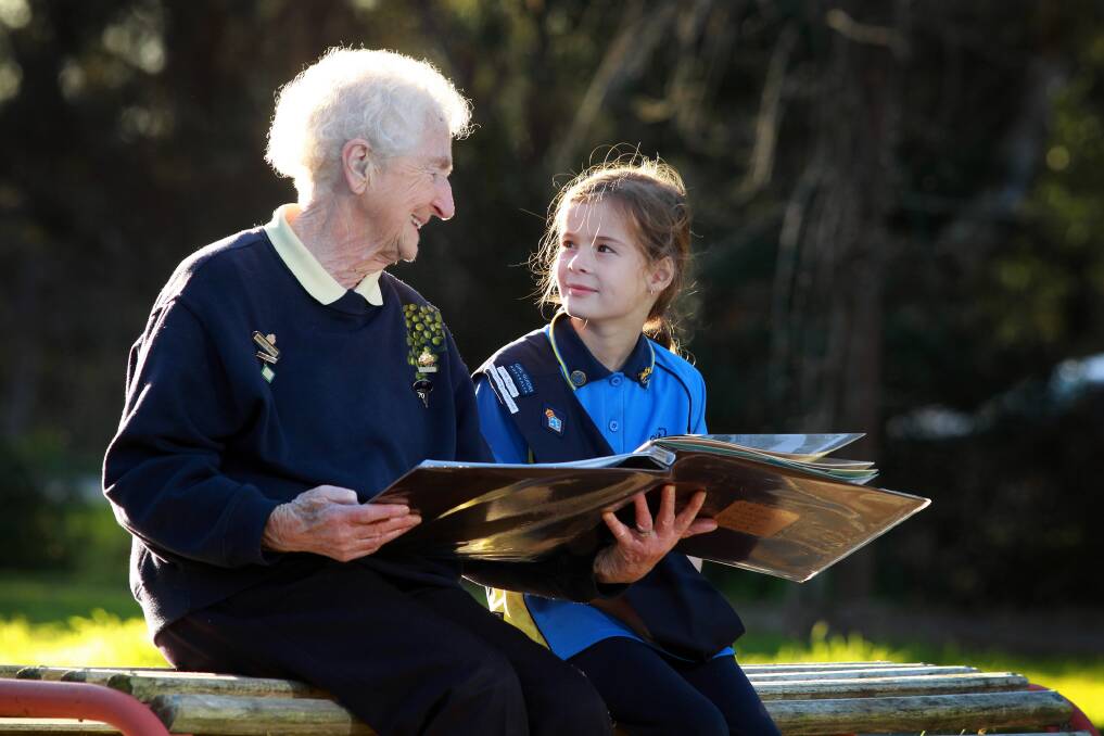 Margaret Eklund, who has been involved with Guides for 83 years, shows Rachel Cooper, 8, from Baranduda, photographs from the history of Girl Guides in Wodonga. Picture: KYLIE ESLER