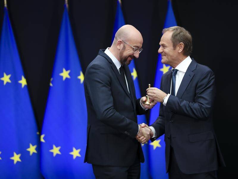 Outgoing European Council President Donald Tusk (R) gives a bell to his replacement Charles Michel.