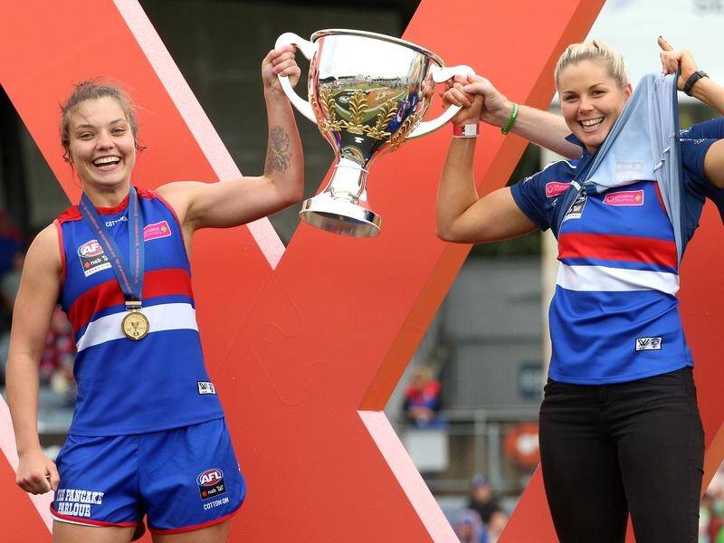 Victorious but controversial - Katie Brennan (r) helps raise the grand final trophy.