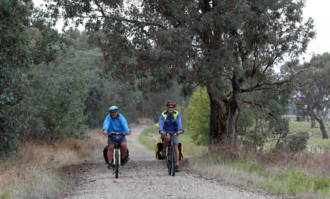 Heiner Schenk and Keith Pike cycle along the rail trail beside Lake Hume near Ebden during their journey. Picture: DAVID THORPE