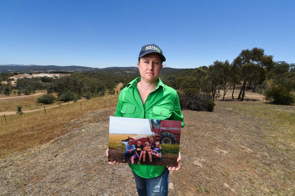 CHANGE: Shelley Scoullar holds a picture of her family husband Paul, Hayden, 14, Lachie, 4, and Jack, 12, taken in April 2019 during their last rice harvest. Picture: MARK JESSER