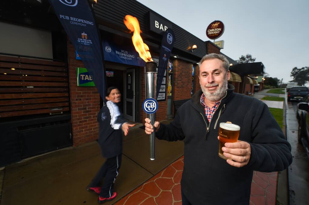 CHEERS: The Blazing Stump Hotel's publican Michael Horsell passes the torch to Deanne McKenzie as part of the Carlton United Brewery official pub re-opening ceremony tour. Picture: MARK JESSER