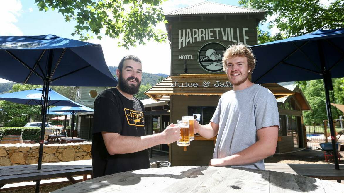 CHEERS: Harrietville Hotel-Motel staff Caleb Lawes and Josh Raymond said it has been great to see the pub thriving a year on from a tough bushfire season. Picture: TARA TREWHELLA