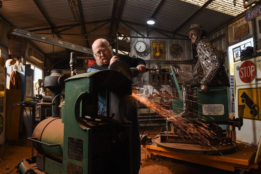 DETAILED: Urana's Andrew Whitehead working on a train, the sculpture of Tim Fischer behind.
