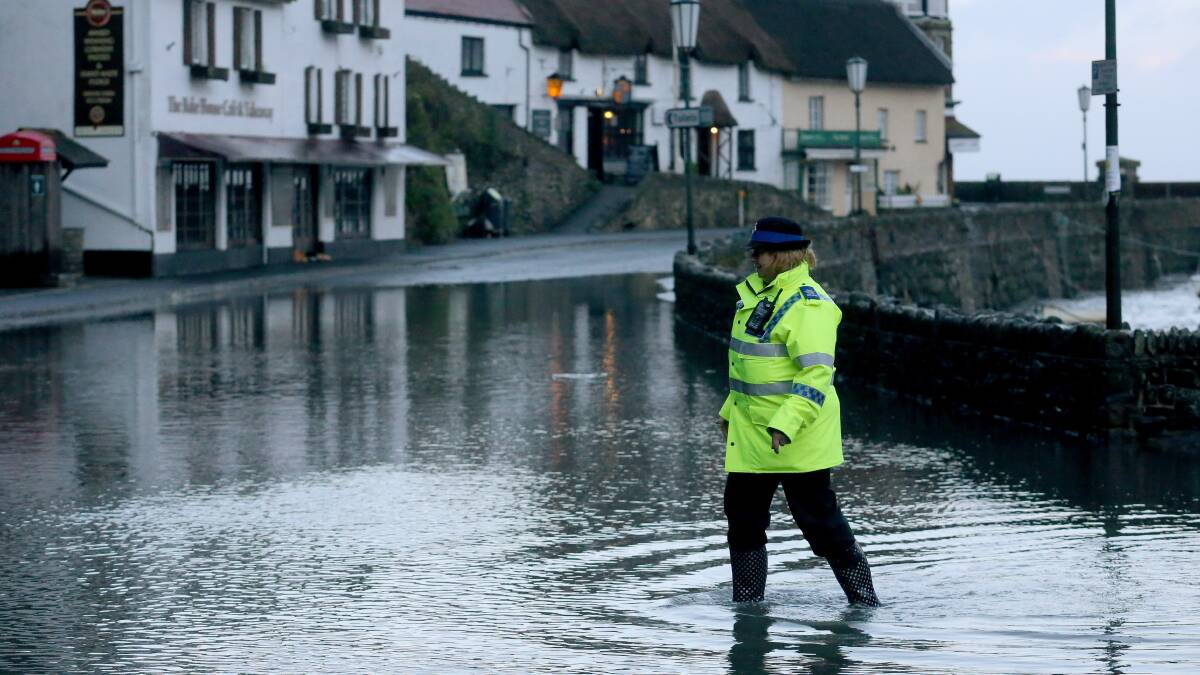  A special constable walks through the high tide flood water that still remains on the seafront at Lynmouth on January 3 in North Devon, England. Picture: Getty