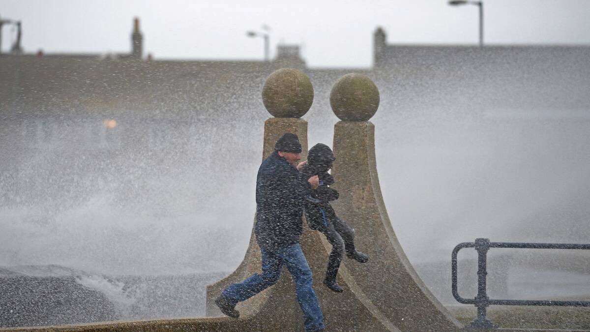 A man and boy take evasive action as waves break over Saltcoats Esplanade on January 3, 2014 in Saltcoats, Scotland. Picture: Getty