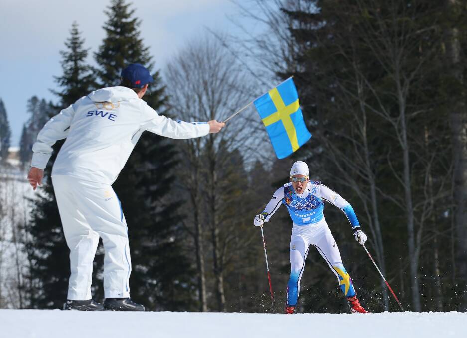 Macus Hellner of Sweden is handed a flag by a team member as he completes the final lap of the Cross Country Men's 4x10km Relay on dey 9 of the Sochi 2014 Winter Olympics at Laura Cross-country Ski & Biathlon Center on February 16, 2014 in Sochi, Russia. Photo: GETTY IMAGES