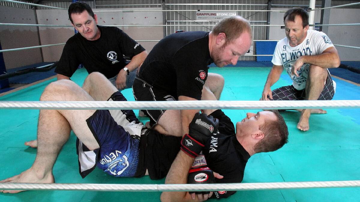 Ben Keenan, floor, and Luke Gooding go about putting the art into martial arts as Tony Morris and John Mee watch the action at the Synergy Training Centre. Picture: KYLIE ESLER
