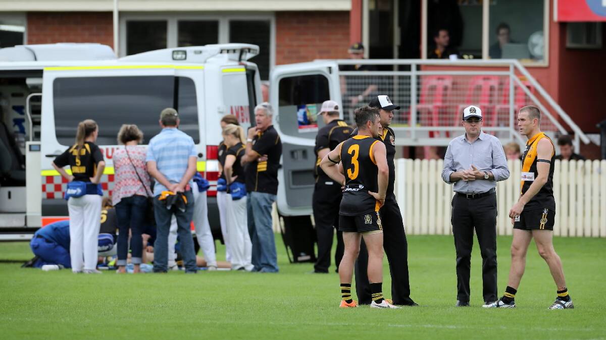 Tigers players and officials talk on the ground as ambulance officers treat James McQuillan who sustained an injury that halted the game. Picture: MATTHEW SMITHWICK