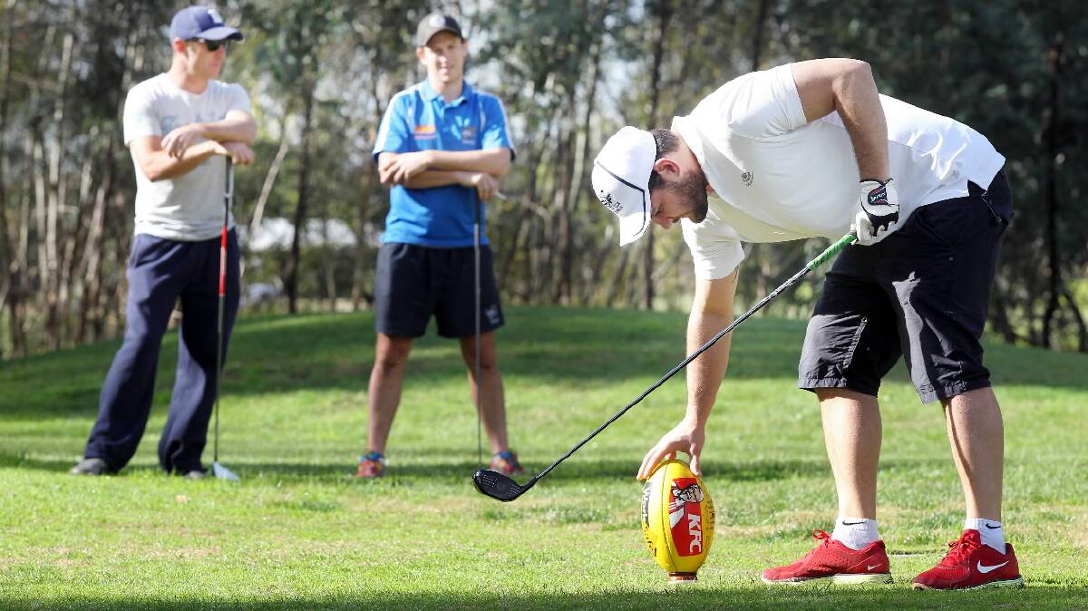 O and M coach Brendan Fevola tees up a more familiar ball at Wodonga Golf Club yesterday as Daniel Maher and Jamie Seymour look on. Picture: KYLIE ESLER