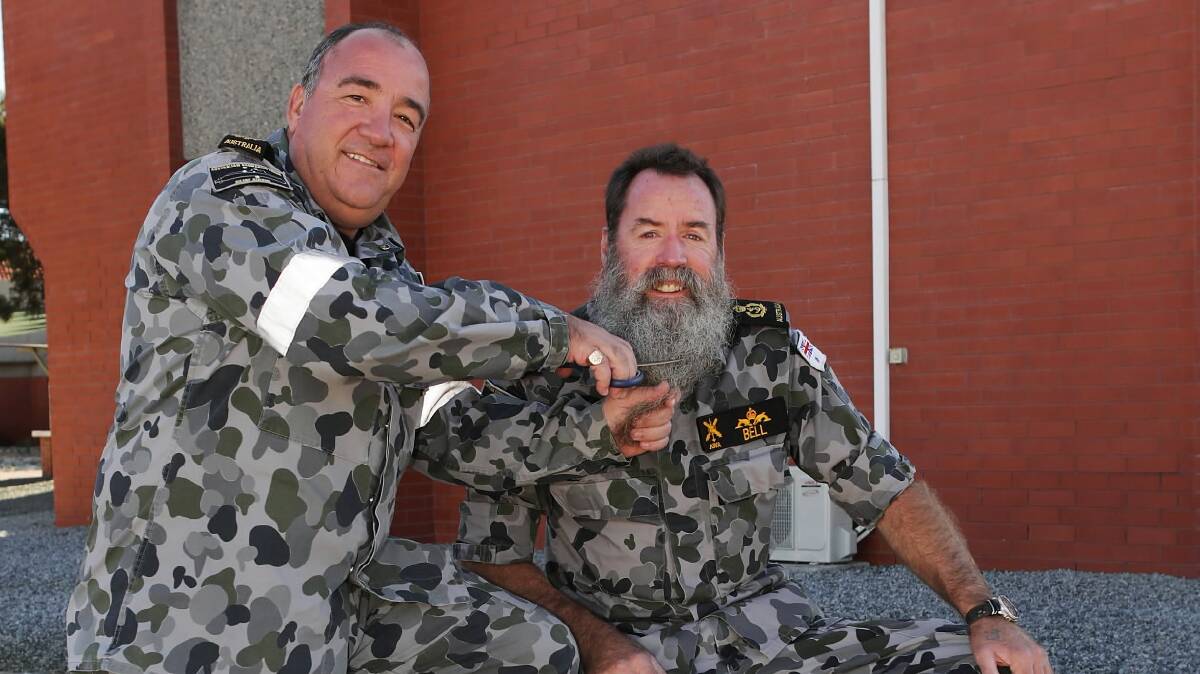 Warrant Officer Mark Dixon gives Chief Petty Officer Mike Bell a brush of the scissors ahead of his Anzac Day beard shave-off at Holbrook. Picture: DEPARTMENT OF DEFENCE