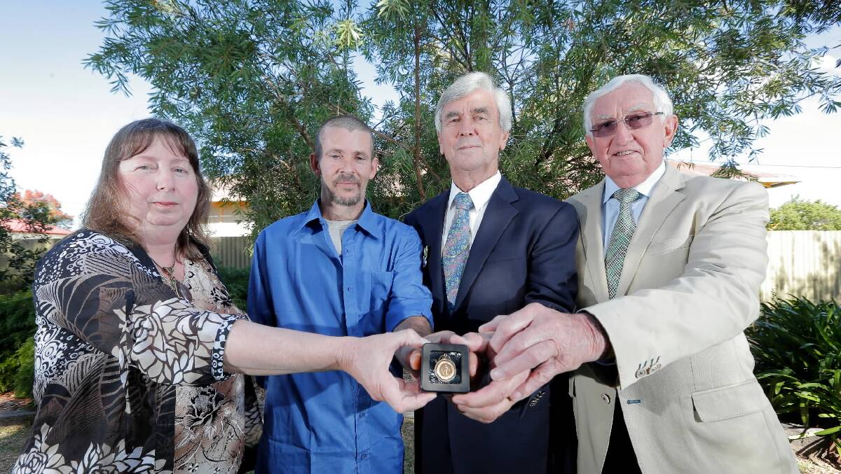 Walla’s Karen Wenke, Darren Blake, of Ganmain, Col Stuart, of Albury, and Neville Stuart, of Canberra holding the medallion, which was returned to the 
Stuart family yesterday after Mr Blake found it at Morgan’s Lookout last year, which was decades after it went missing. Picture: TARA GOONAN