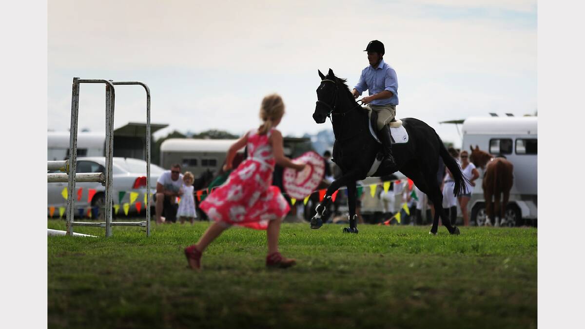 A girl runs past as an equestrian rider practices.