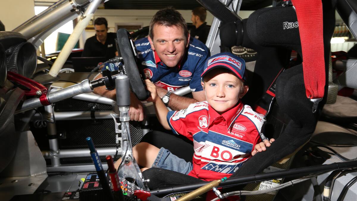 Brad Jones Racing driver Jason Bright and Wangaratta's Brodie Pearson, 9, sit in the brand new car that Brodie donated his pocket money towards building. Pictures: MATTHEW SMITHWICK