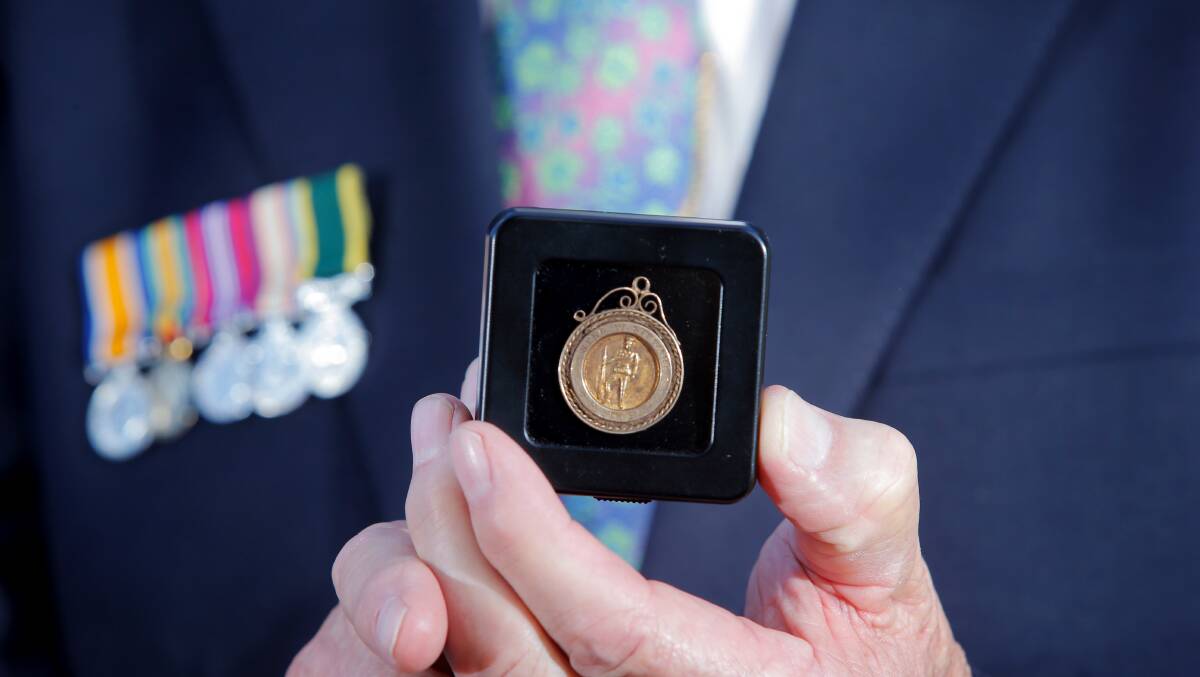 A veteran holds up his medals at the Anzac Day service in Walla Walla. Picture: TARA GOONAN