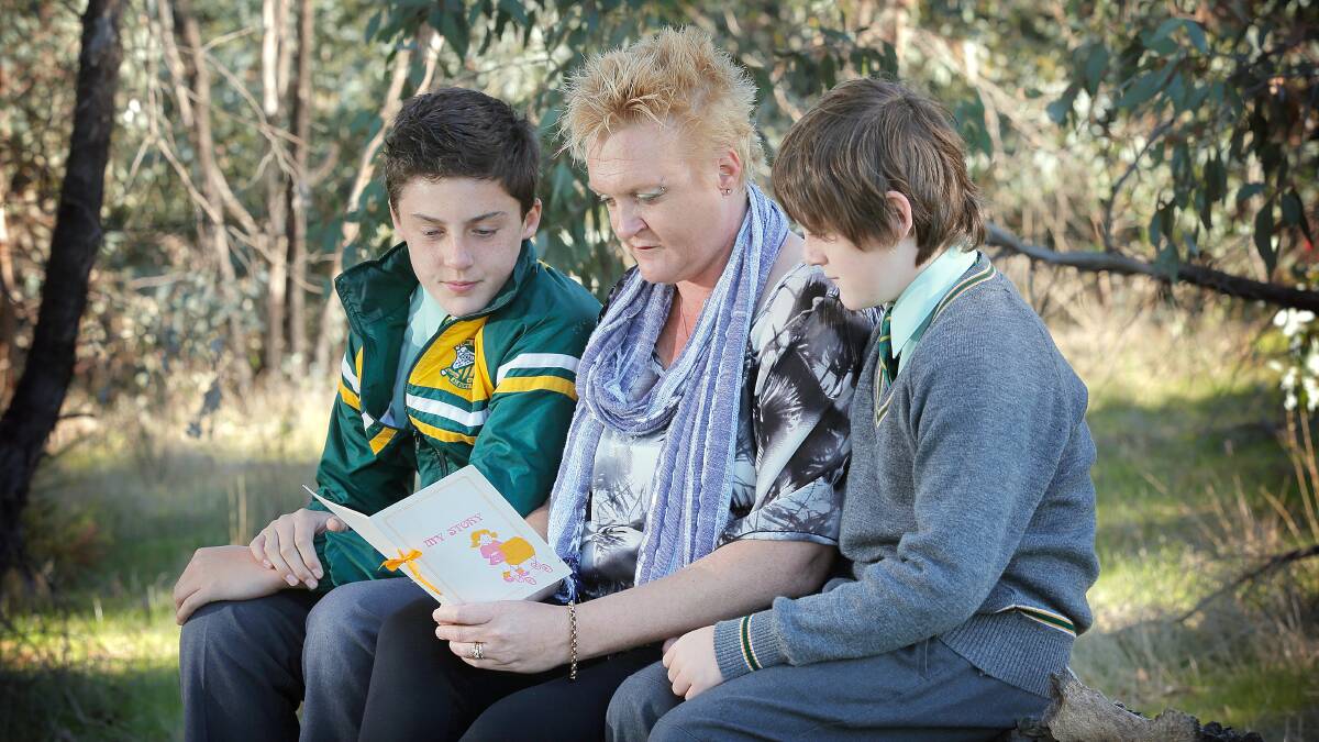 Helen Nicholson, pictured with her two sons Brendan and James (aged 12 and 9), looking at the booklet she was given when she was 12 to tell her about her birth parents. Picture: TARA GOONAN