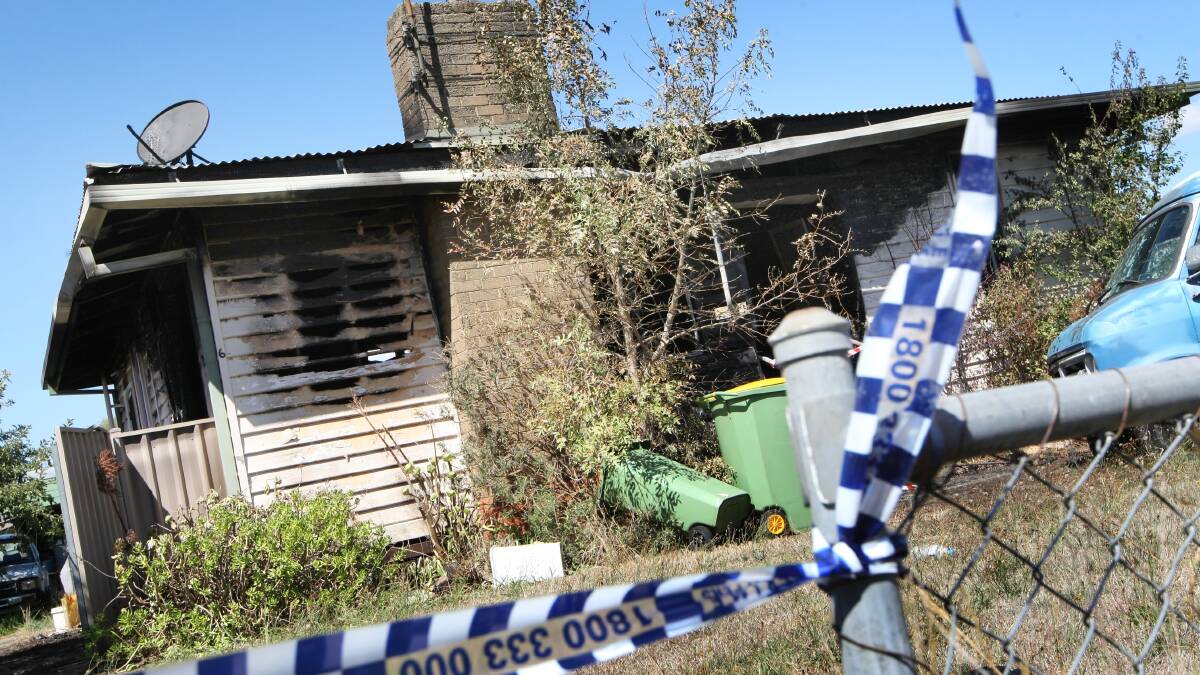 Forensic investigators look over the scene of a house fire on Le Couteur Avenue at Beechworth yesterday. 