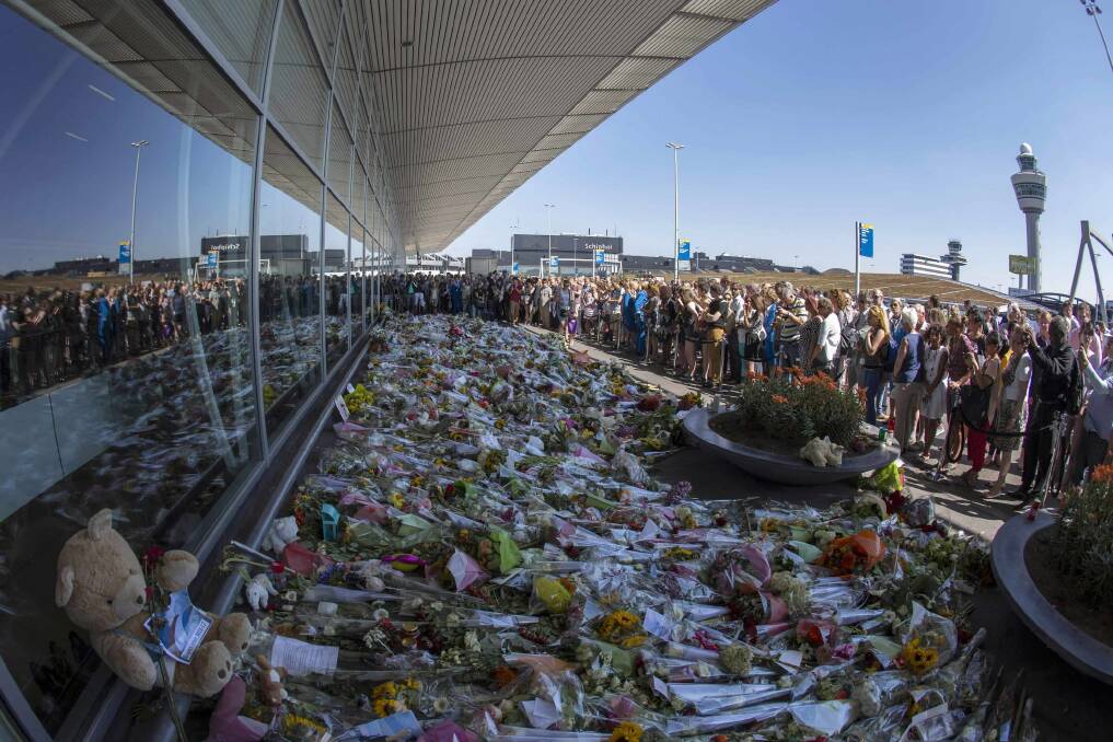 Flight attendants and mourners gather near flower bouquets as they pay their respects at Schiphol Airport during a national day of mourning for the victims of the downed Malaysia Airlines flight MH17. Picture: REUTERS/