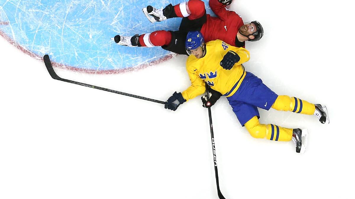 Julien Vauclair #3 of Switzerland falls to the ice with Jimmie Ericsson #42 in the first period during the Men's Ice Hockey Preliminary Round Group C game on day seven of the Sochi 2014 Winter Olympics at Bolshoy Ice Dome. Photo by Bruce Bennett REMOTE/Getty Images
