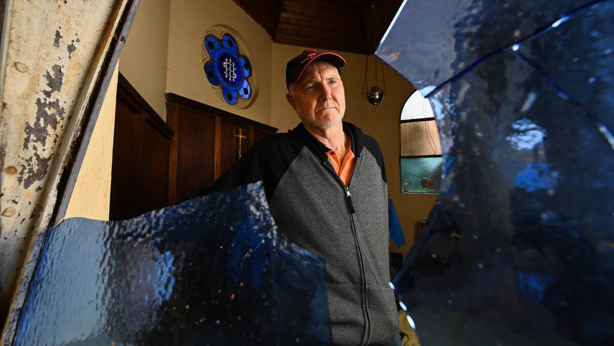DAMAGE BILL: Treasurer Kevin Fisher with one of the many smashed windows at the Barnawartha church, which has been recently been targeted twice. Picture: MARK JESSER