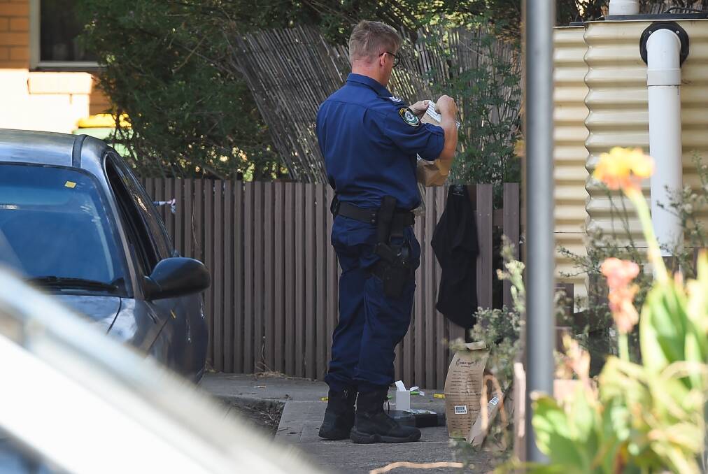 CRIME SCENE: A forensic officer seals an evidence bag at the Mate Street property. Police removed a large number of items from the scene. Pictures: MARK JESSER