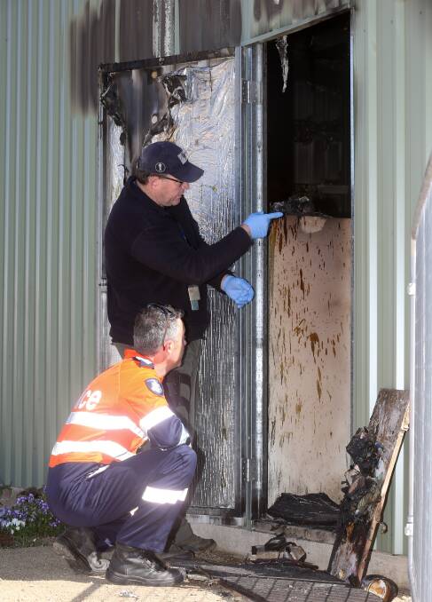 CRIME SCENE: Detectives Graeme Simpfendorfer and Ray Causer examine the scene of the blaze at the Wodonga Cemetery in October last year. 