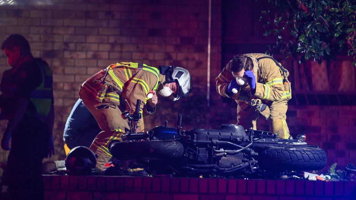 ON SCENE: Firefighters inspect the crashed motorcycle on Saturday night. 
