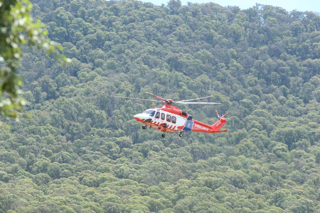 The crash was just 300 metres from the Mt Buffalo National Park, pictured behind the air ambulance. Picture by Blair Thomson