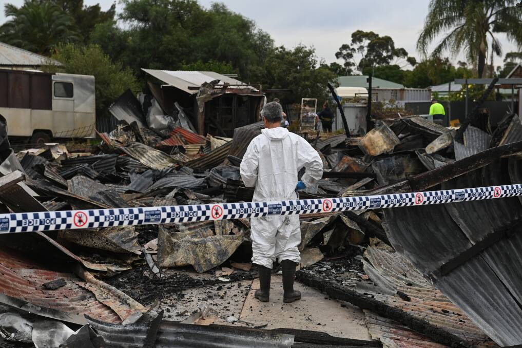 INVESTIGATION: A fire investigator searches through the flattened Urana business on Monday. 