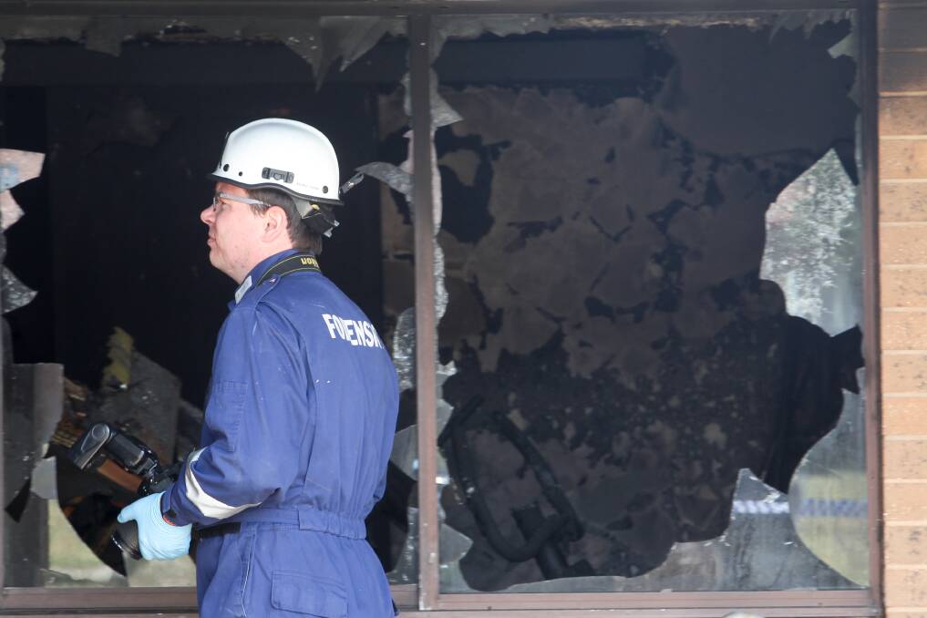 INVESTIGATION: A forensics officer examines the Stevenson Street property in Wodonga the day after the incident. The public housing home was gutted by flames. 
