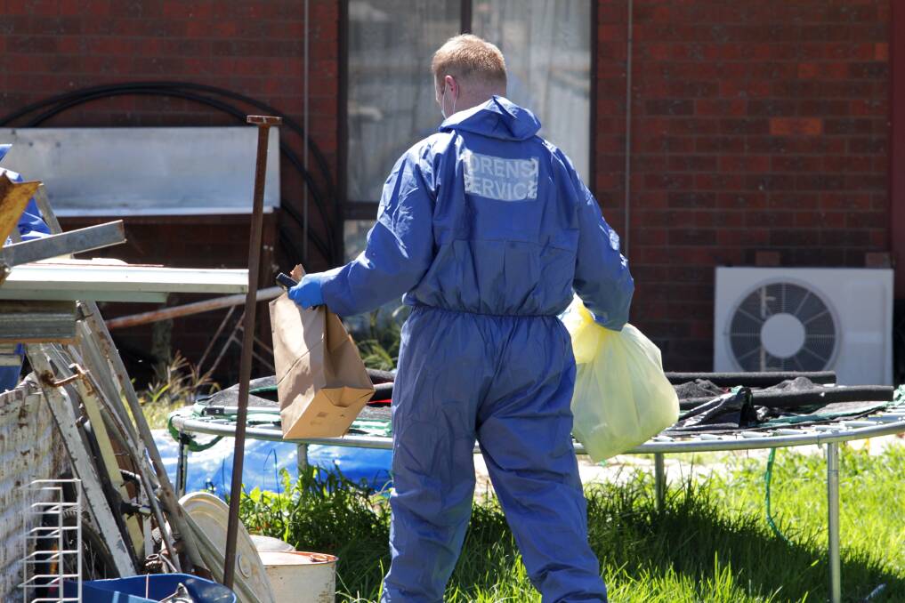 EVIDENCE: A forensic officer with items at the Church Street property last week. Multiple bags of evidence were removed from the home, which was littered with various items, by investigators.