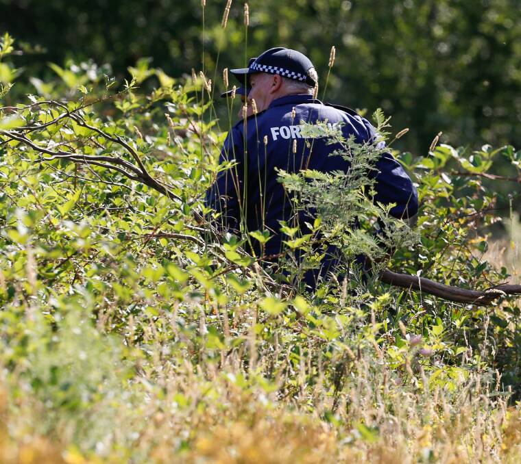 CRIME SCENE: A forensic officer examines the area where the body was found. Pictures: MARK JESSER