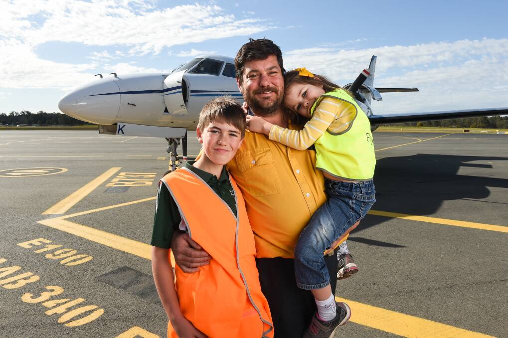 WELCOME BACK: Shai Feuerherdt with his children Harry, 12, and Eliza, 5, after touching down at Albury Airport. They were relieved their father arrived safely following three nights fighting fires in challenging conditions. Picture: MARK JESSER