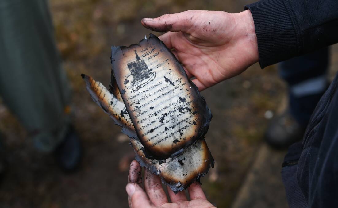 DAMAGED: Mr Tolley holds a part of a book that was burnt during the house fire. Pictures: MARK JESSER